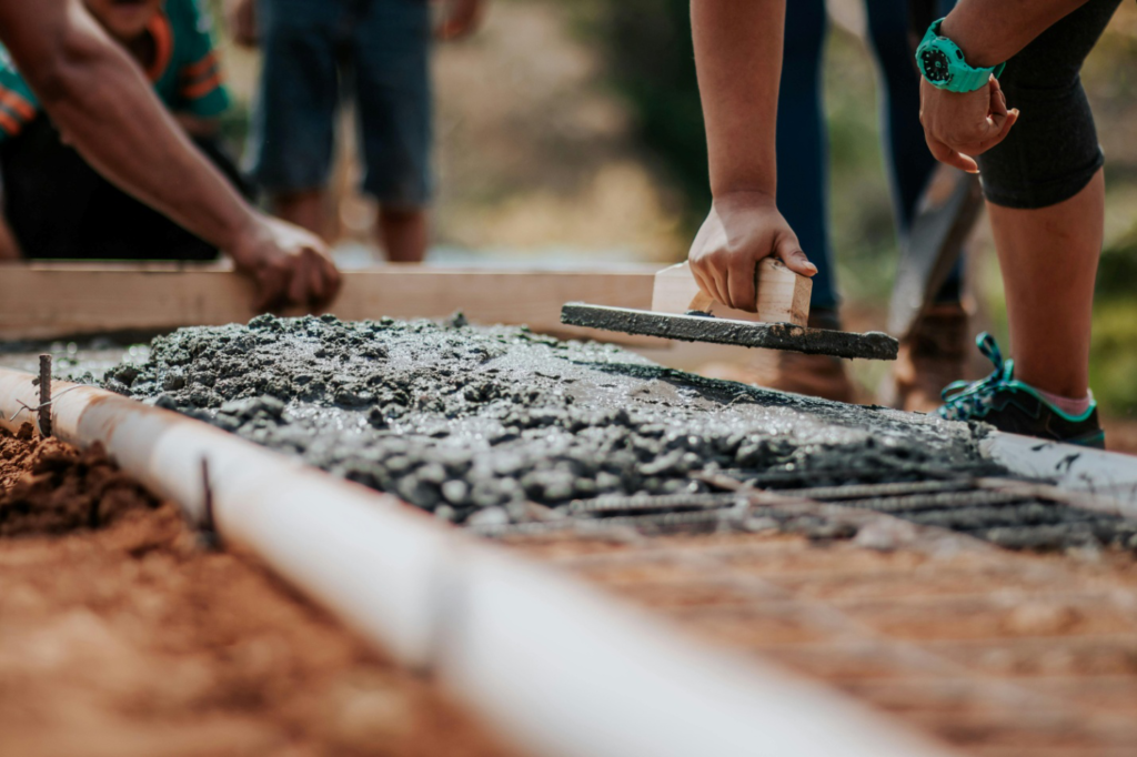 focused shot of workers laying down cement foundation