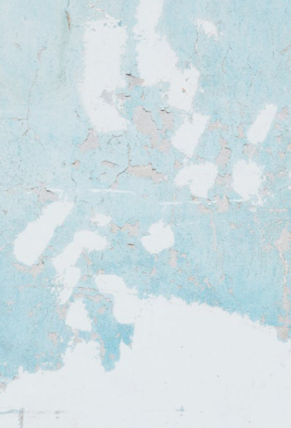 Peeling blue and white paint on a weathered wall showing signs of water damage