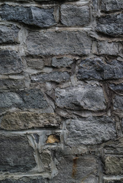 Rough-textured stone wall with visible mortar joints and signs of wear