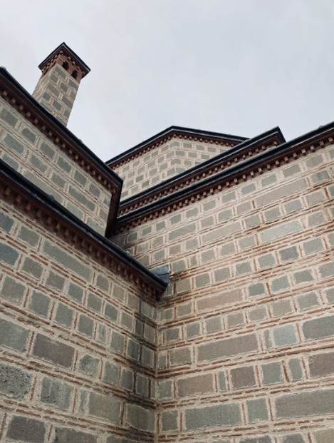 Modern brick masonry building with intricate detailing and a chimney against a cloudy sky