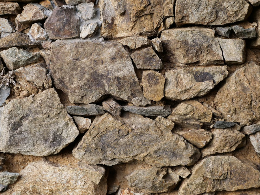 An irregularly shaped stone wall with brown and gray tones showing signs of weathering