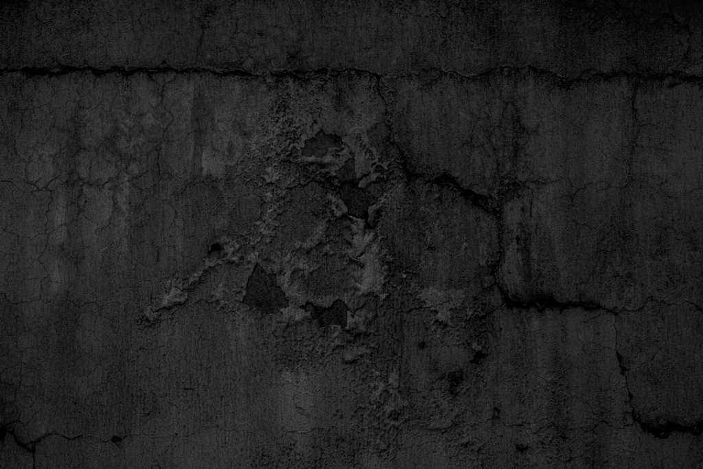 Close-up of a dark, cracked, and distressed wall surface