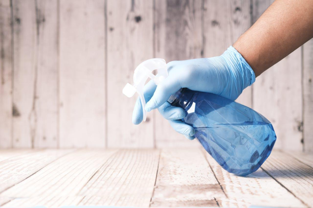 A spray bottle with a cleaning formula is being sprayed on wood
