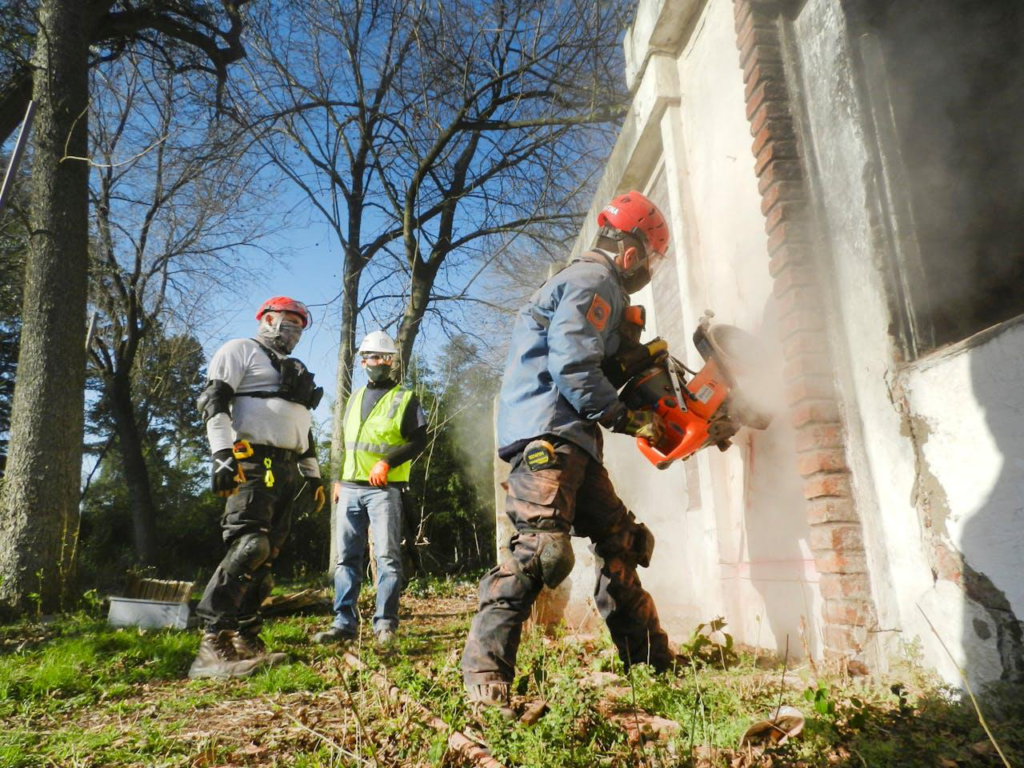 3 professional masonry workers are standing and installing a brick wall