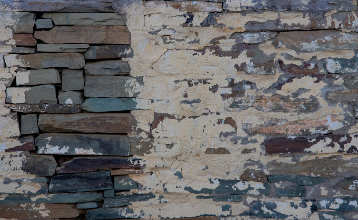 damaged brick wall with grey bricks exposed and wall paint chipping off