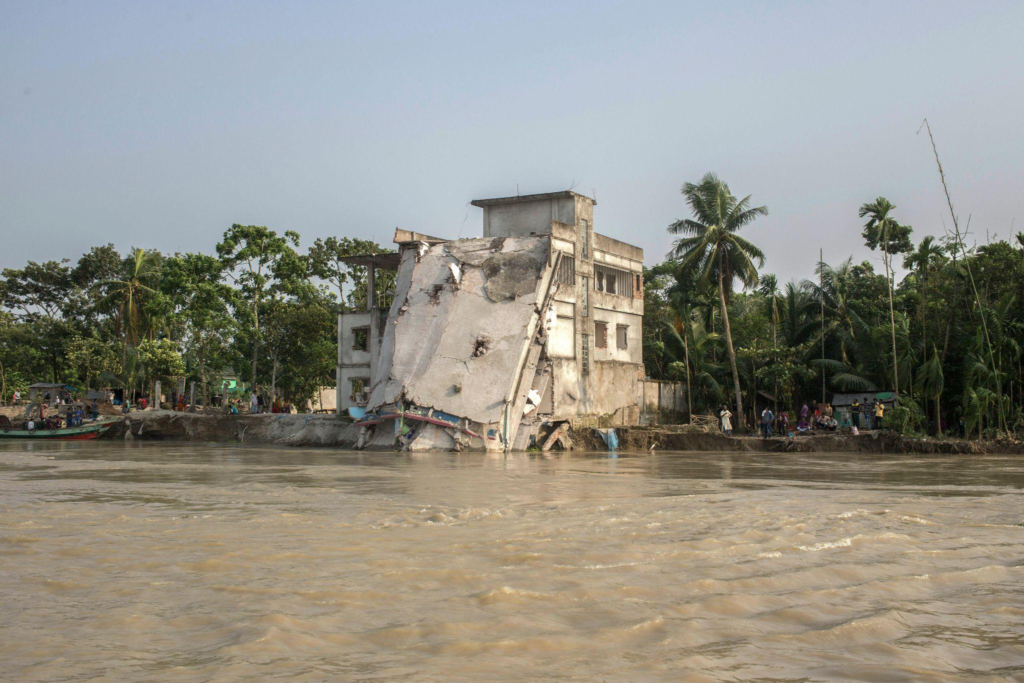 A completely wrecked building on the shore showing severe water damage.