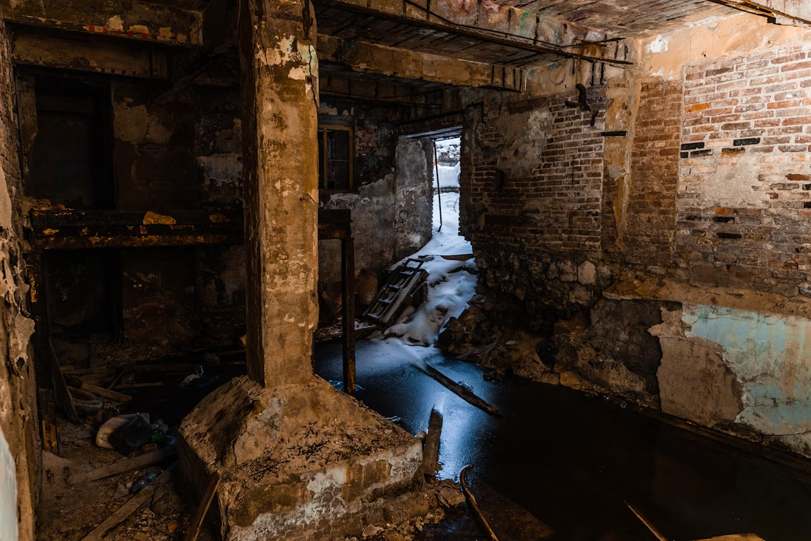 Abandoned basement with water seeping through cracked concrete and stone walls