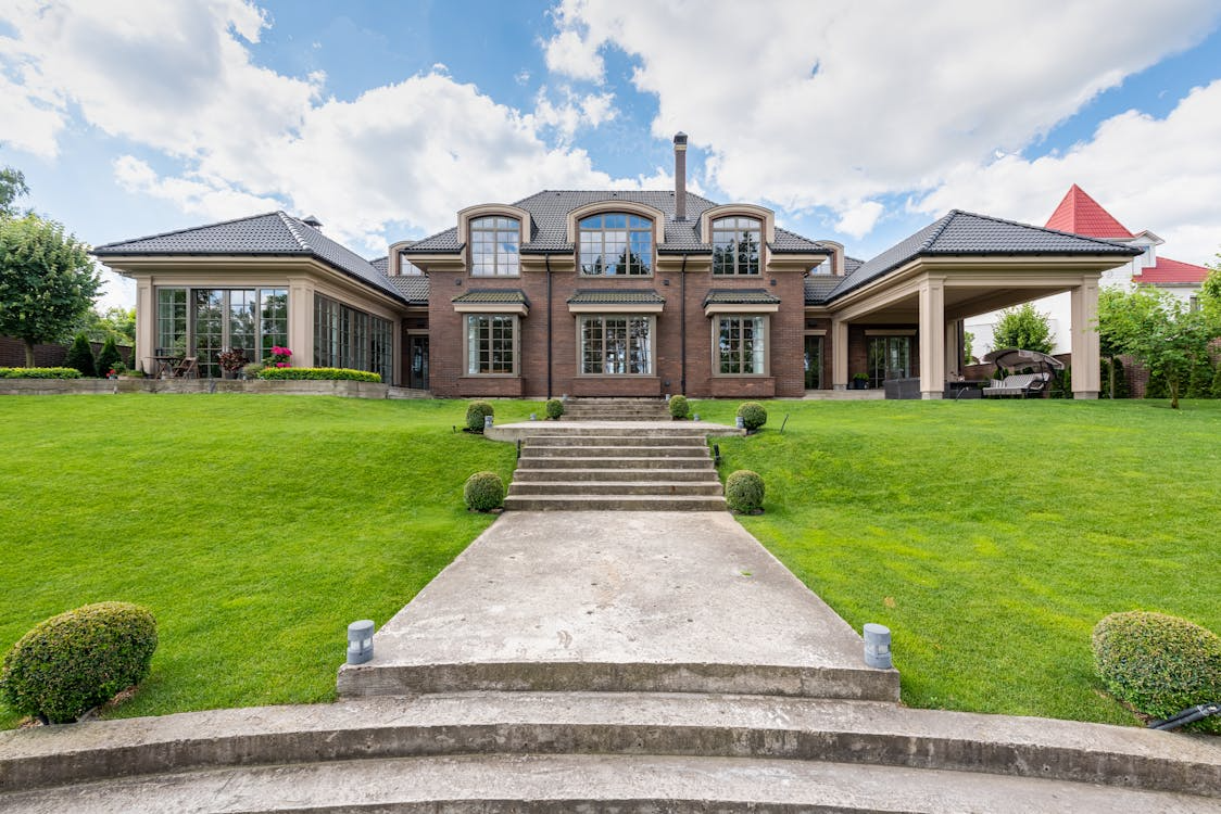 Front view of a large estate with stone and brick exterior walls under a cloudy sky