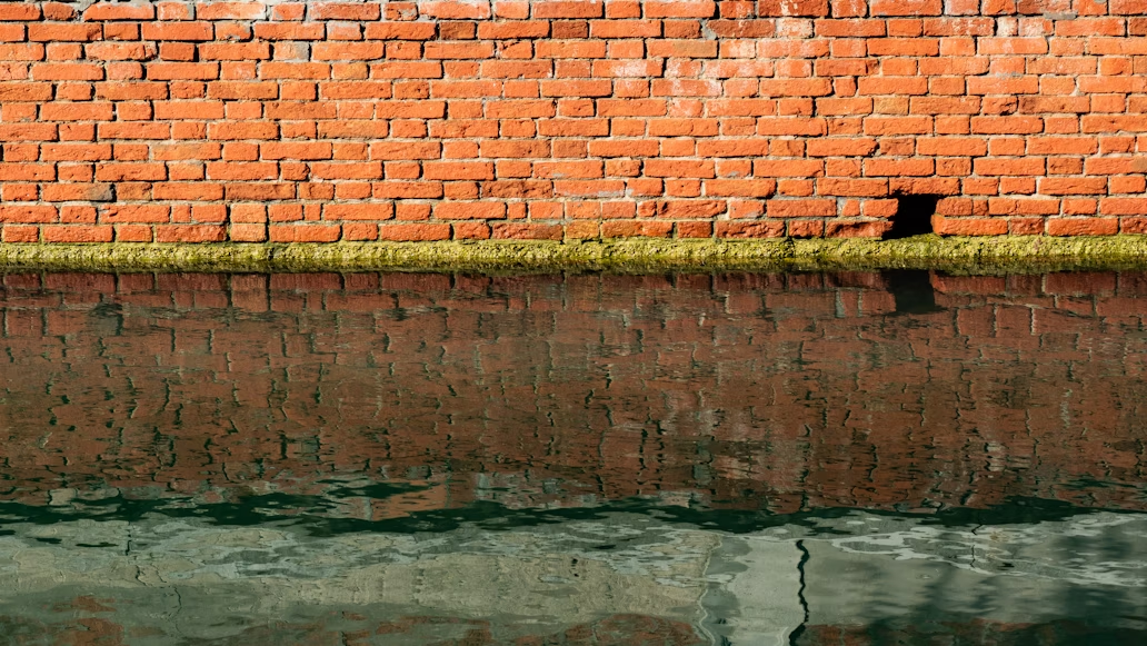 A brick wall reflected in a pool of water.