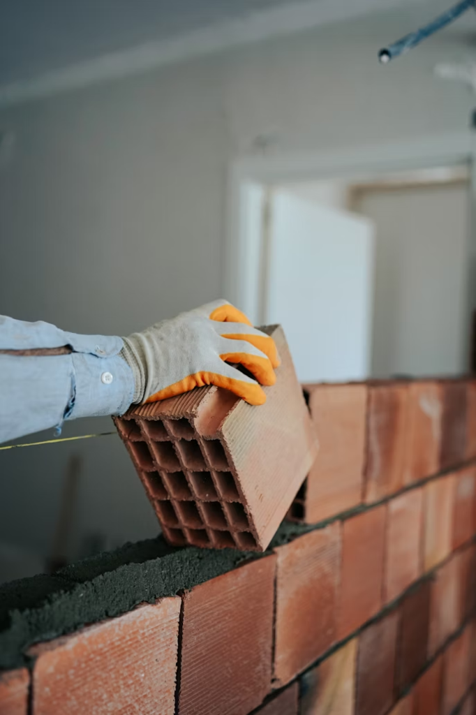A photo of a workman’s hand holding a brick.