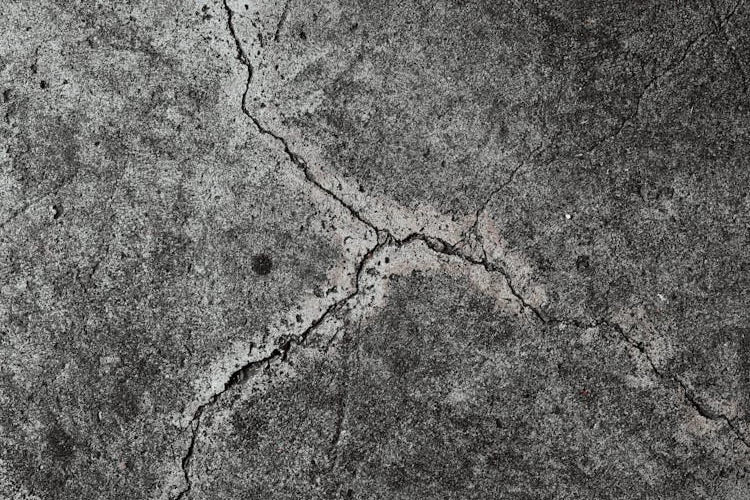 Cracked and dry concrete surface showing deep fractures and weathering.