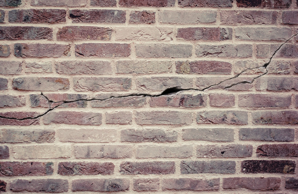 A cracked brick wall showing a horizontal fracture through the mortar and bricks.