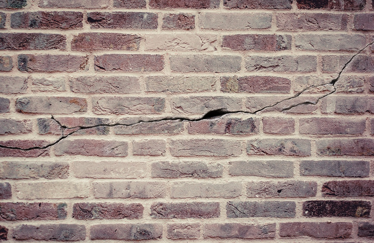 A cracked brick wall showing a horizontal fracture through the mortar and bricks.