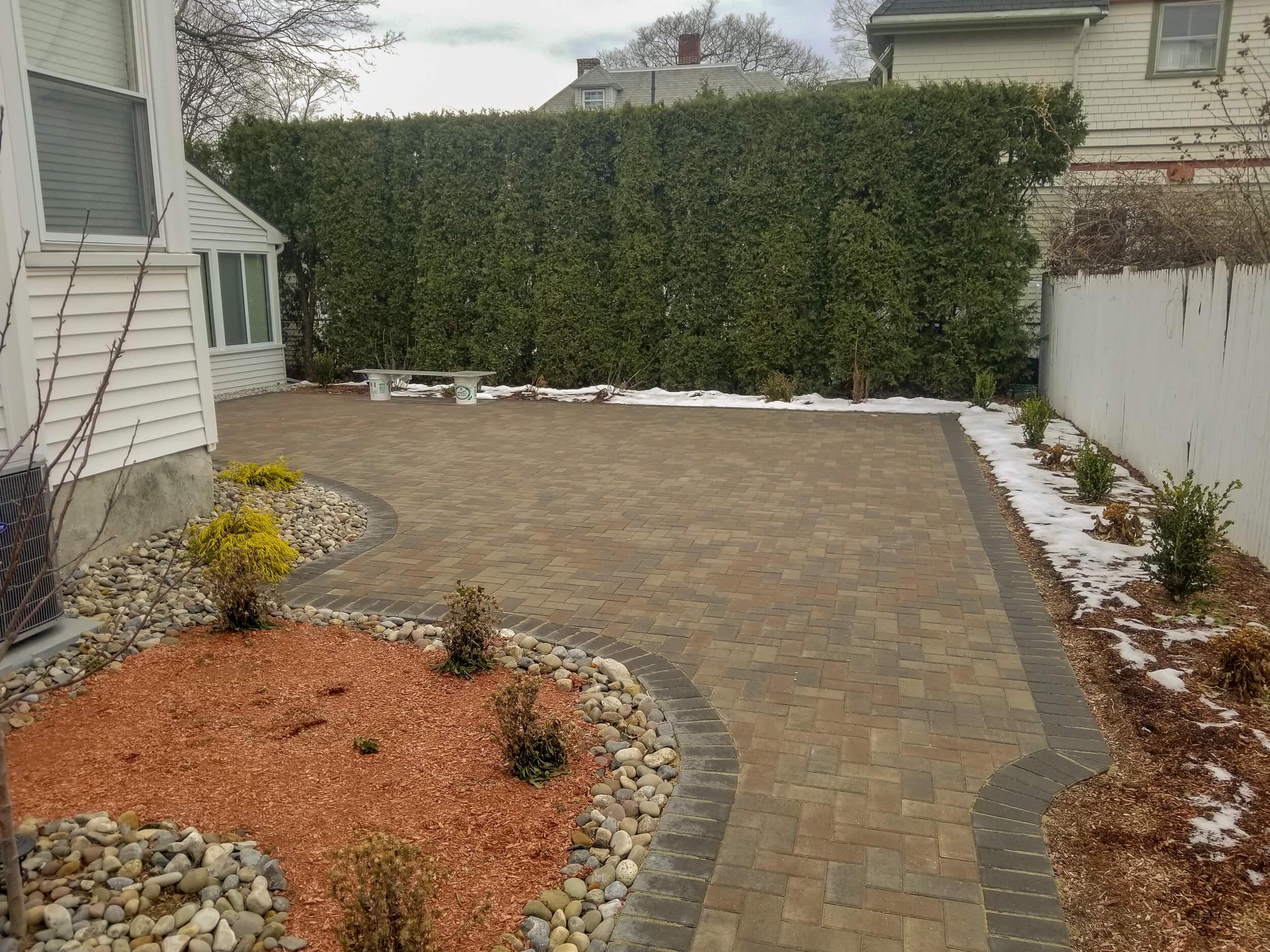 Interlocking paver patio and walkway beside home prepared for winter conditions