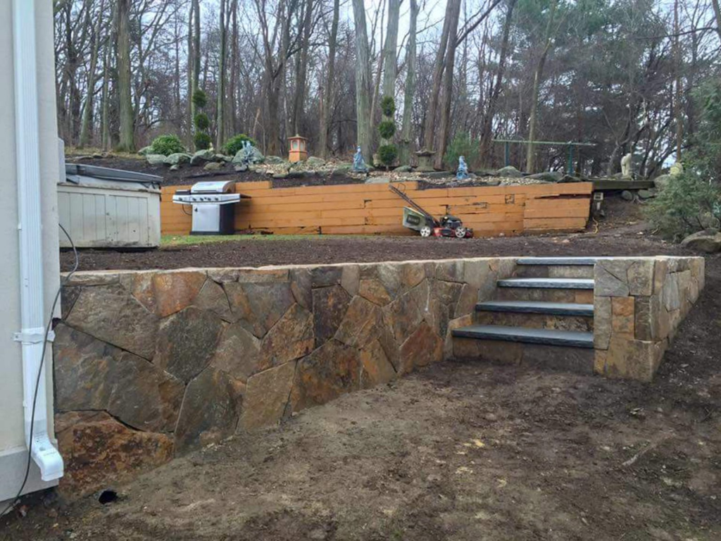 Retaining wall restoration contractors reinforcing wall with proper drainage and masonry repairs