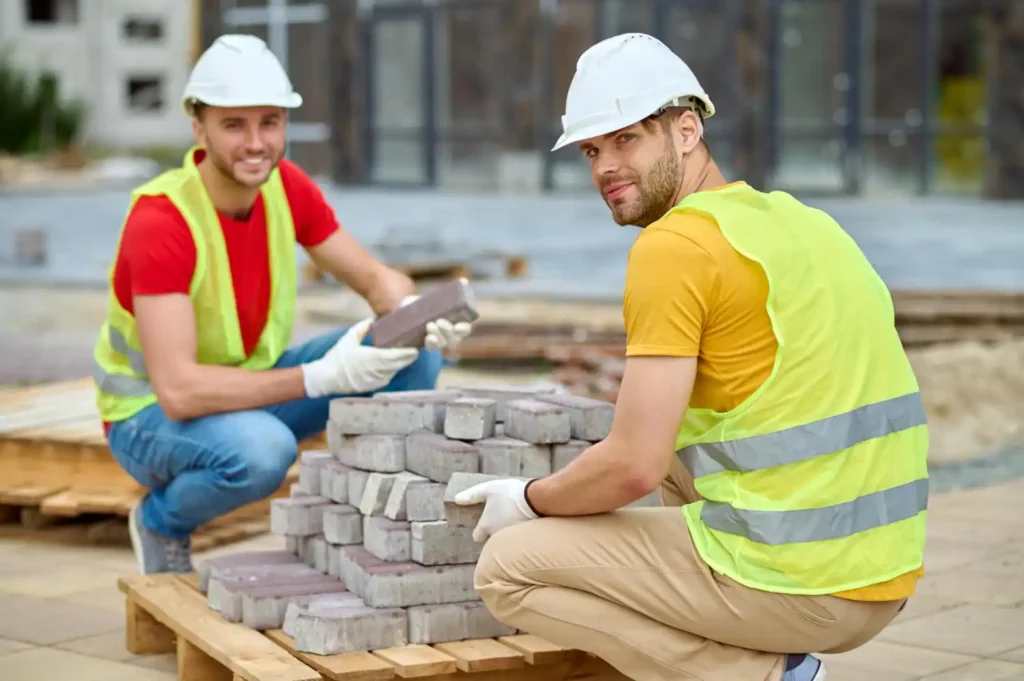 This photo shows some workers with bricks in front of them.