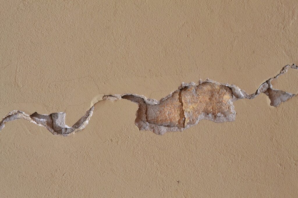 Interior wall with visible cracking and surface damage caused by prolonged moisture exposure.
