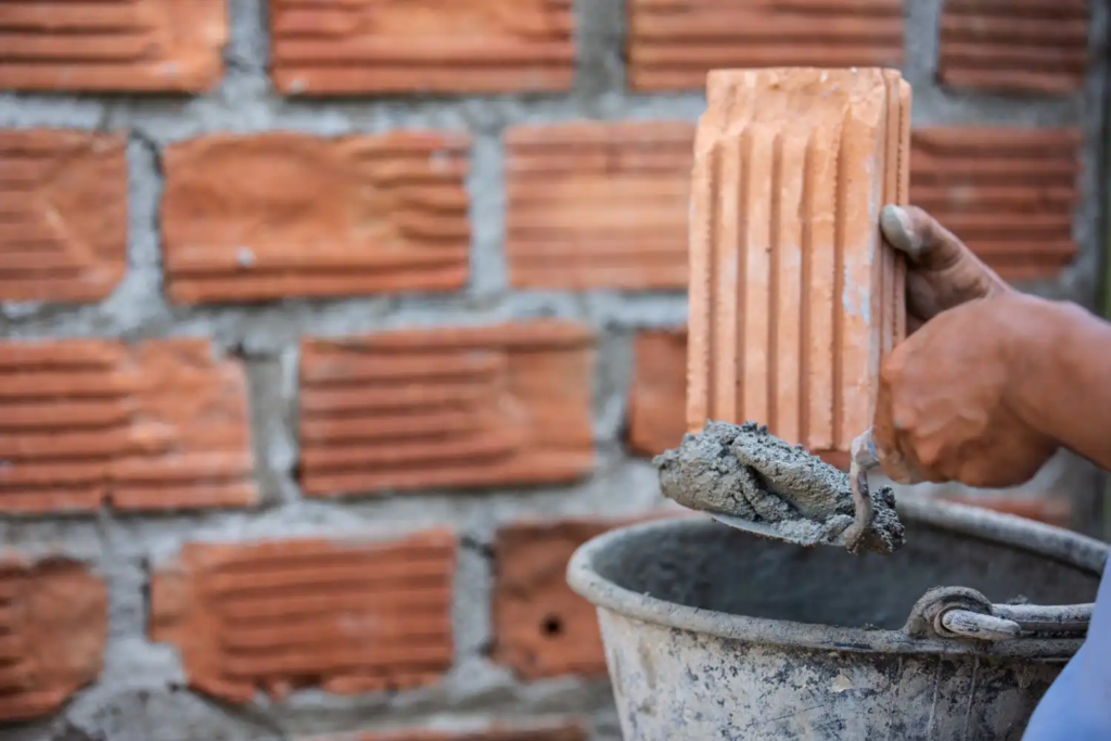 Masonry worker applying mortar during brick and stone repair work on a building exterior.