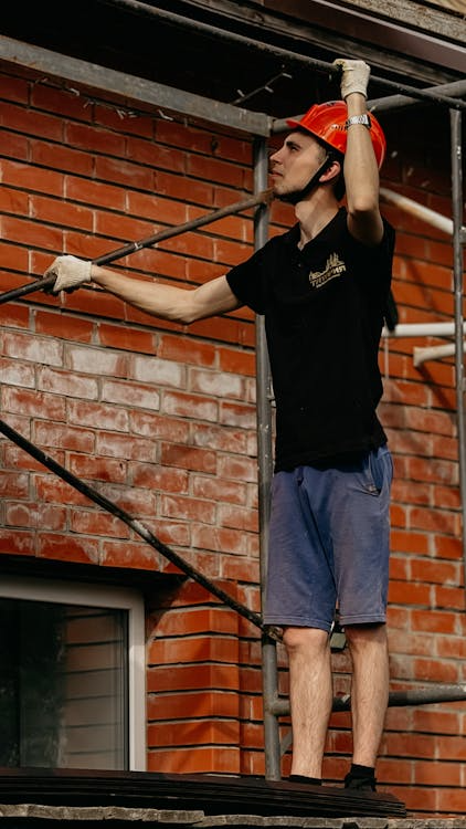 Masonry contractor working on brick restoration and repointing to preserve structural stability and appearance.